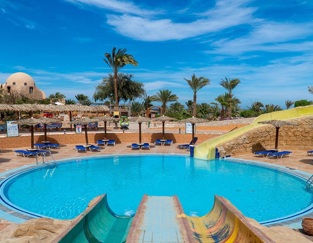Außenpoolbereich des Utopia Beach Club Hotels mit Rutschen und Liegestühlen.