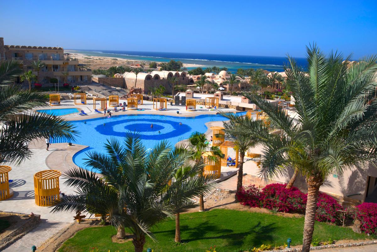 Luftaufnahme des Utopia Beach Club Resorts mit Swimmingpool und Meer im Hintergrund.