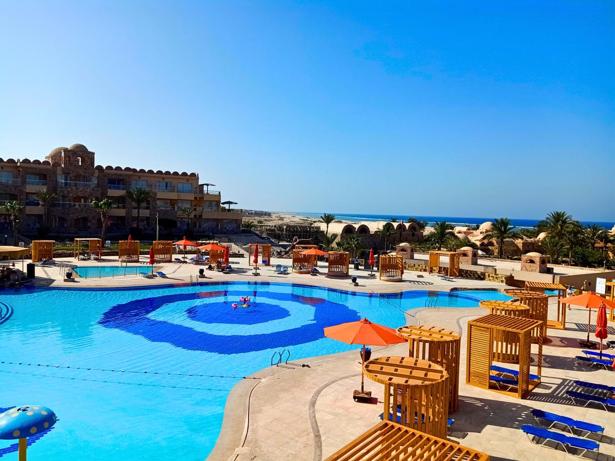 Aussicht auf den Poolbereich des Utopia Beach Club Hotels mit mehreren Schwimmbecken und Sonnenschirmen.