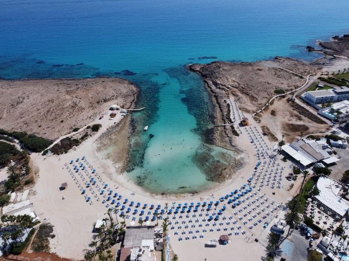 Luftaufnahme des Anonymous Beach mit blauem Wasser und vielen Liegestühlen