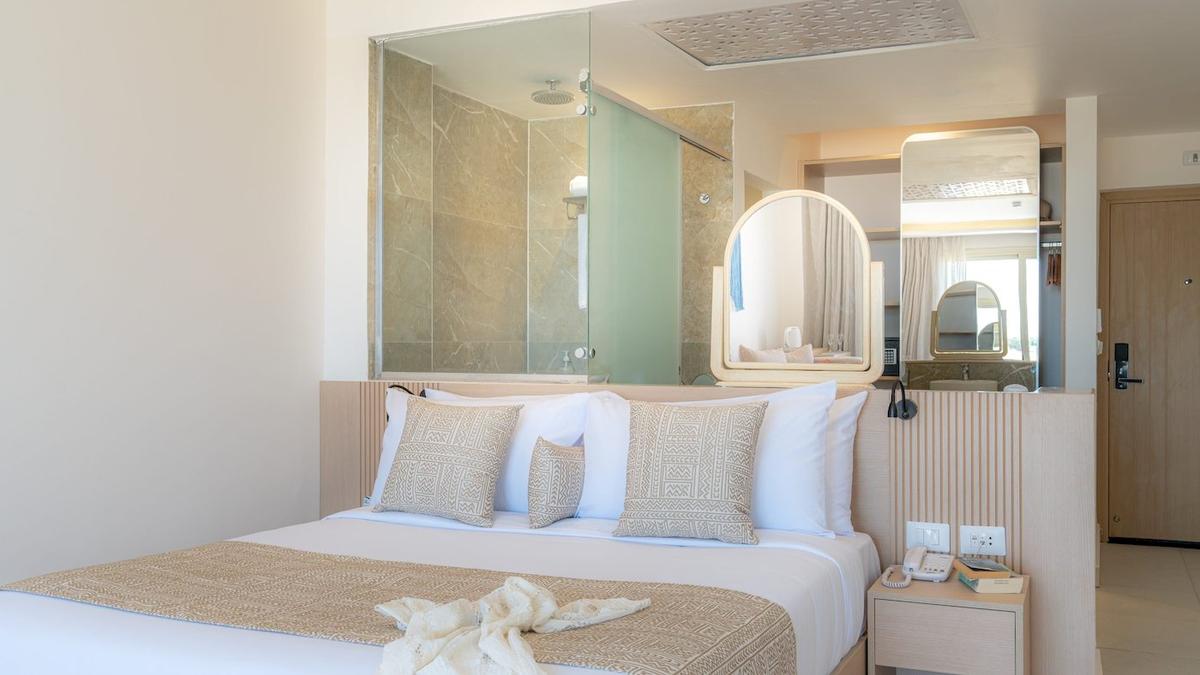 Schlafzimmer im Three Corners Equinox Beach Resort mit Bett und Badezimmerspiegel