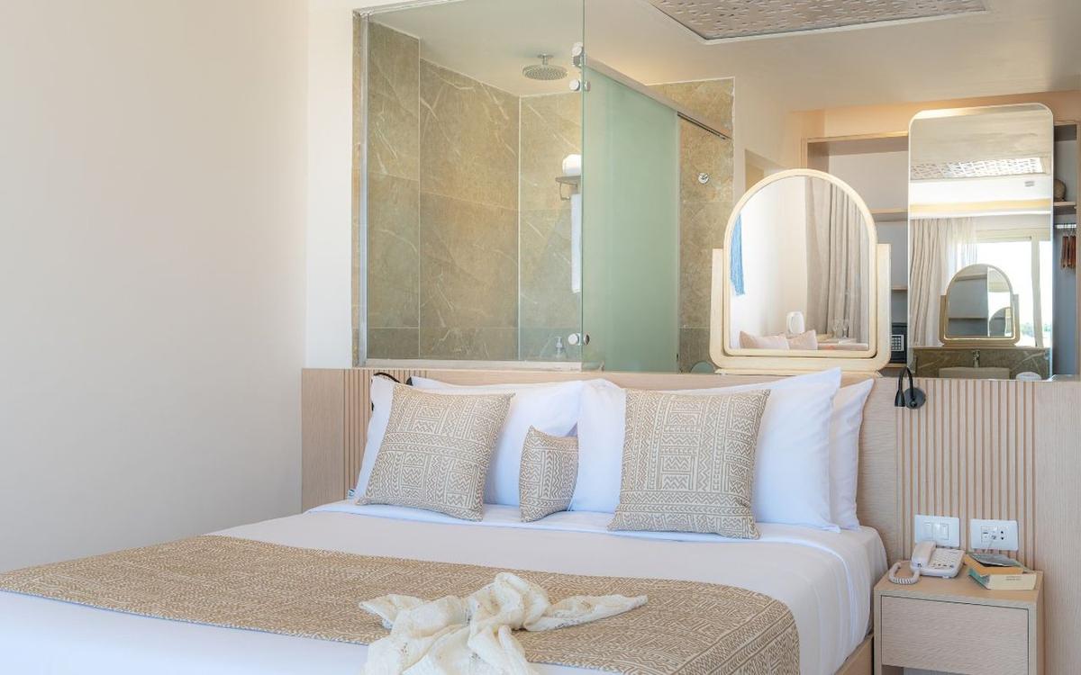 Schlafzimmer im Three Corners Equinox Beach Resort mit großem Bett, Dekor und Badezimmerspiegel