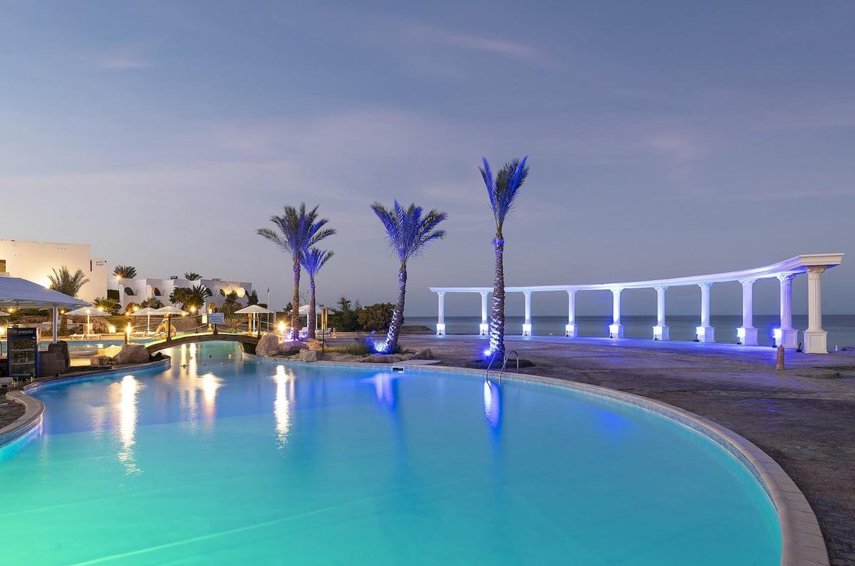 Ein Pool im Three Corners Equinox Beach Resort bei Nacht, beleuchtet von blauen Lichtern.