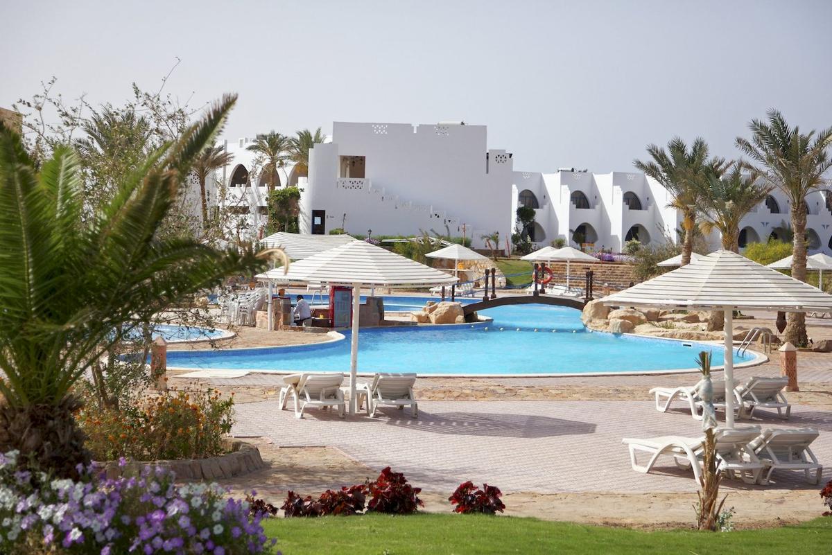 Ein Swimmingpool im Freien mit weißen Sonnenliegen und großen Sonnenschirmen im Three Corners Equinox Beach Resort.