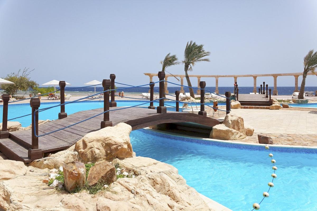 Ein Pool mit einer hölzernen Brücke im Three Corners Equinox Beach Resort