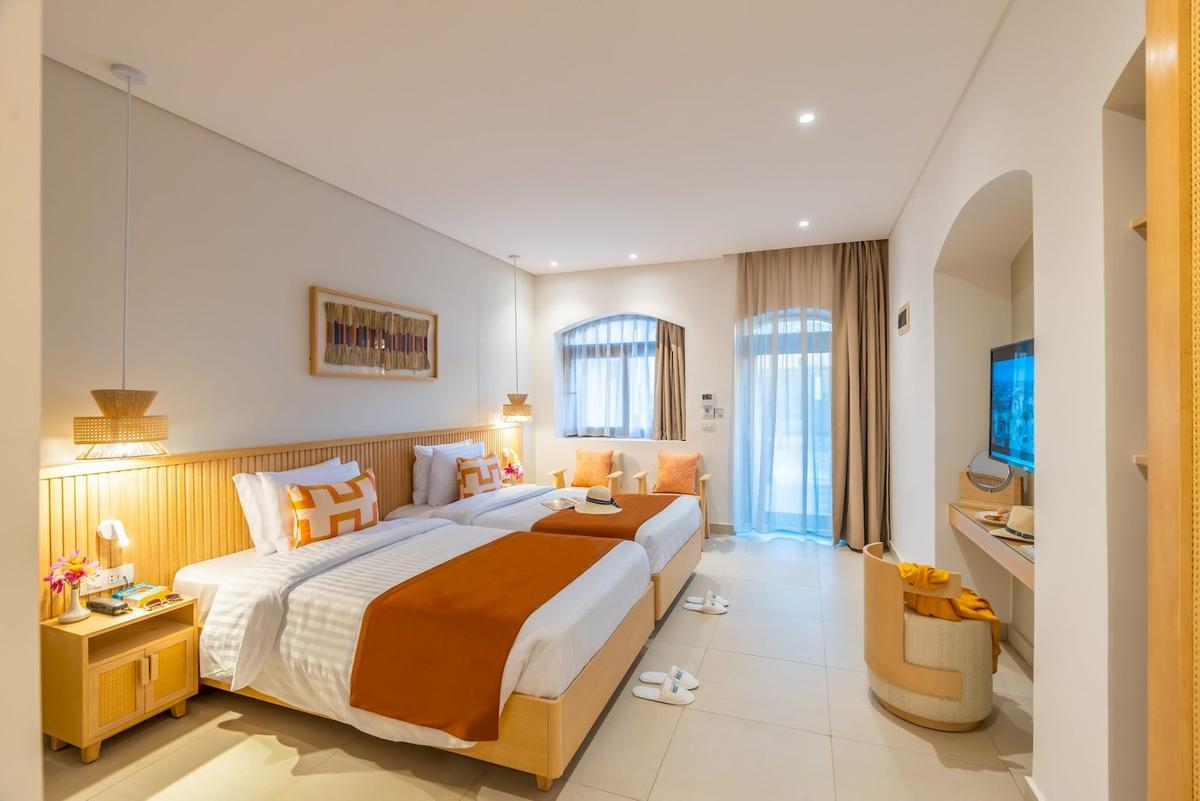 Doppelzimmer im Three Corners Rihana Resort mit zwei Betten, Dekor und Fenstern.