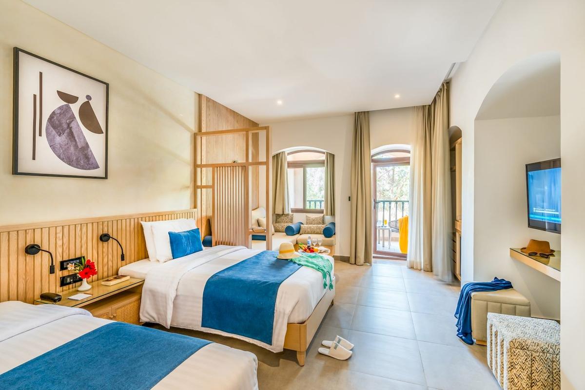 Ein Hotelzimmer im Three Corners Rihana Resort mit zwei Betten, einem Fernseher und einer Terrasse.