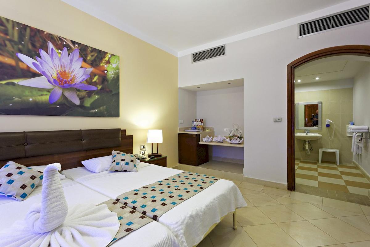 Doppelzimmer im Three Corners Rihana Resort mit zwei Betten, einer Lotusblume an der Wand und einem Badezimmer.