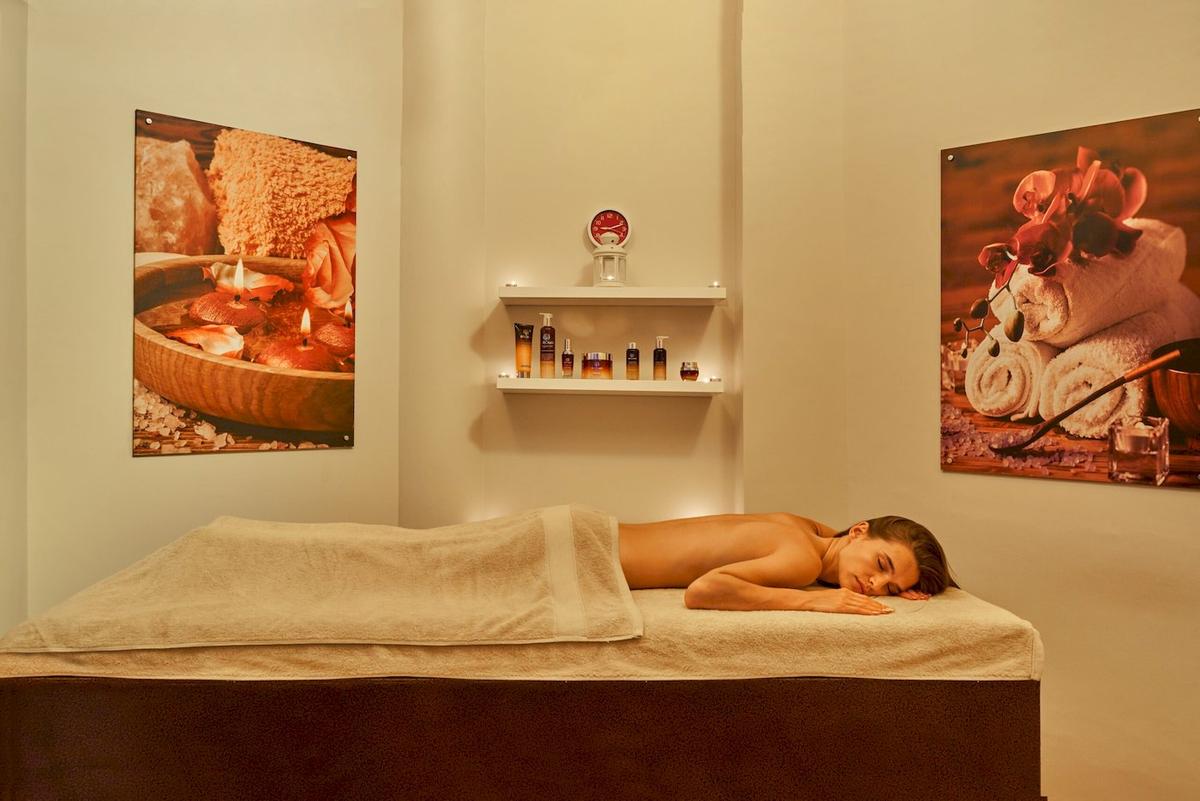 Spa-Behandlung im Three Corners Rihana Resort mit Frau, die auf einem Massagebett liegt.