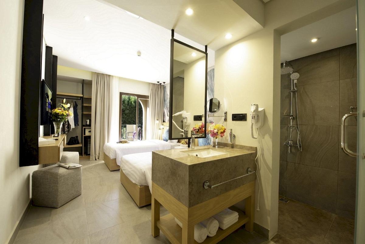 Innenansicht eines Doppelzimmers im Three Corners Rihana Resort mit zwei Betten, Waschbecken und Dusche.
