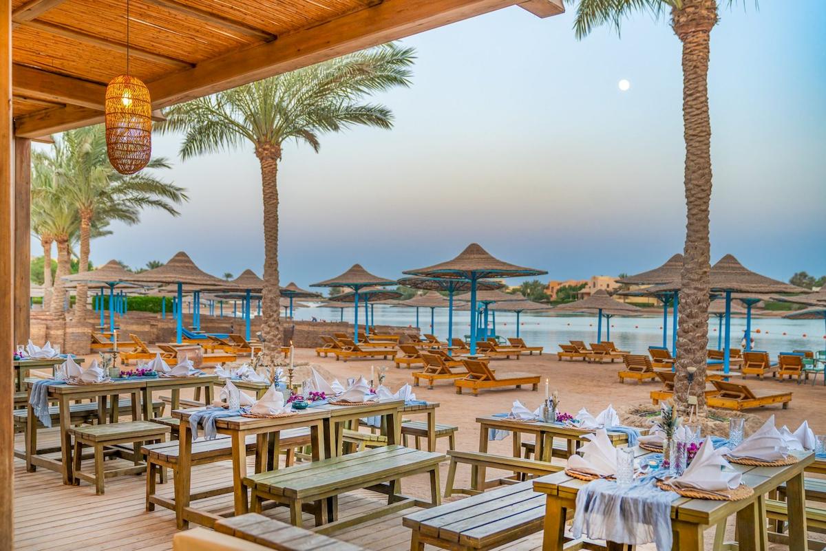 Abendessen-Setup im Freien am Strand des Three Corners Rihana Resorts mit Palmen und Sonnenliegen