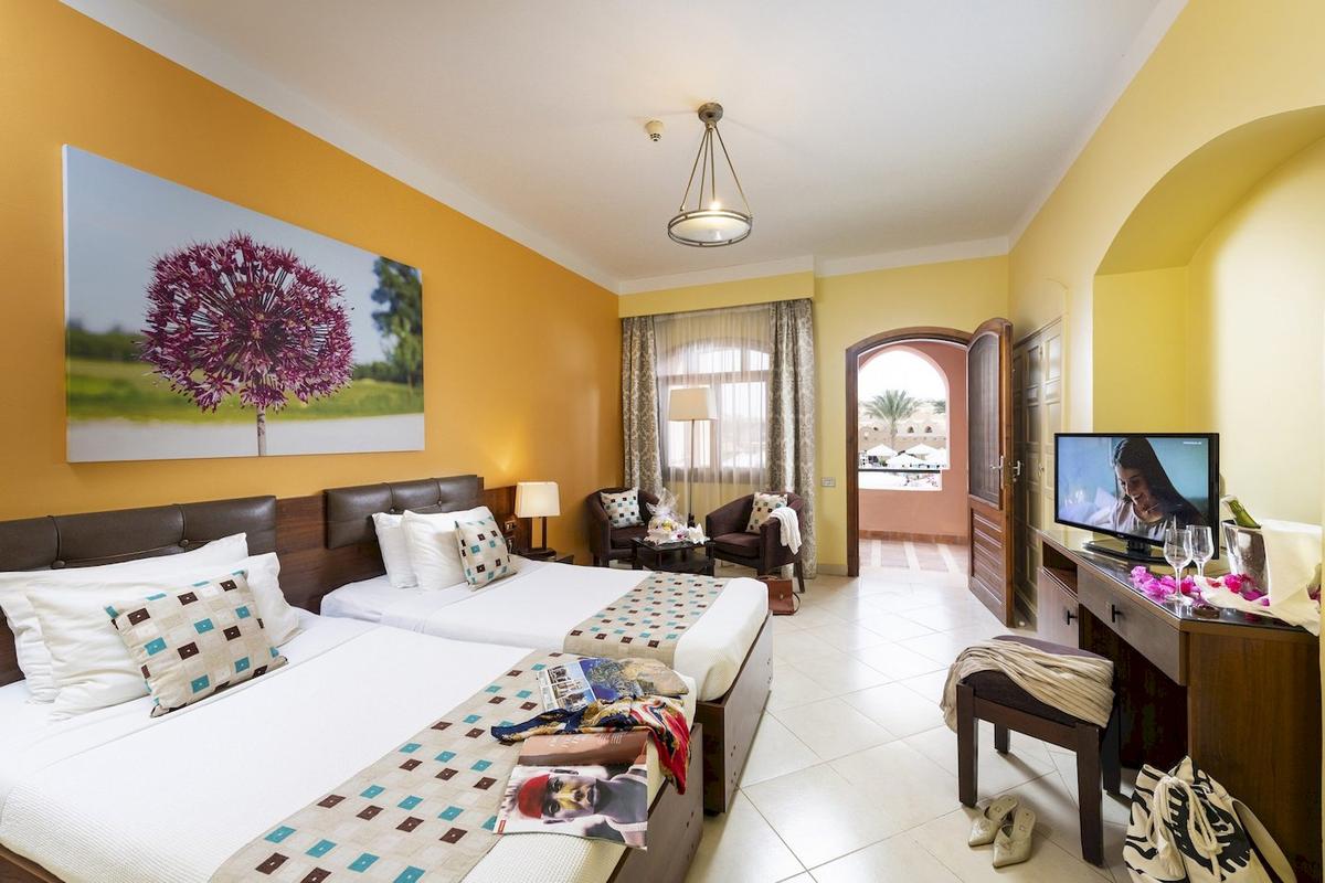 Zwei Betten in einem Hotelzimmer des Three Corners Rihana Resort mit Dekor und Möbeln.
