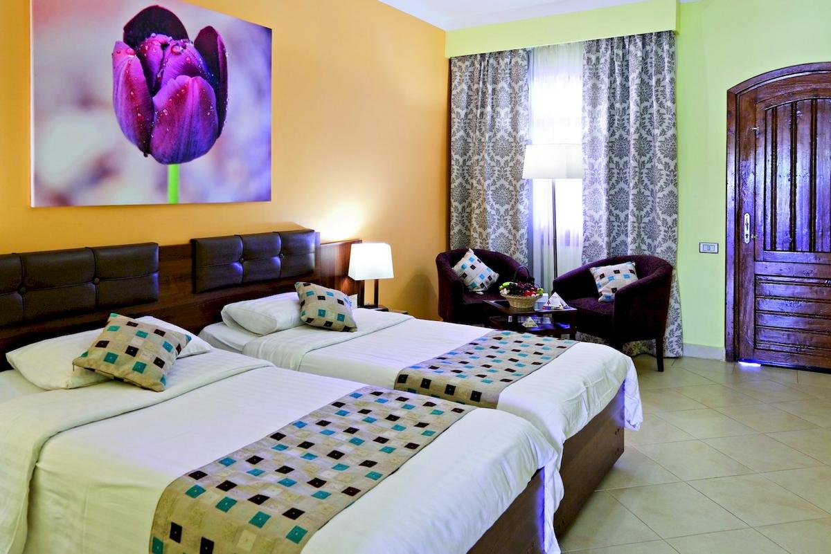 Zwei Betten mit gemusterten Tagesdecken im Zimmer im Three Corners Rihana Resort.