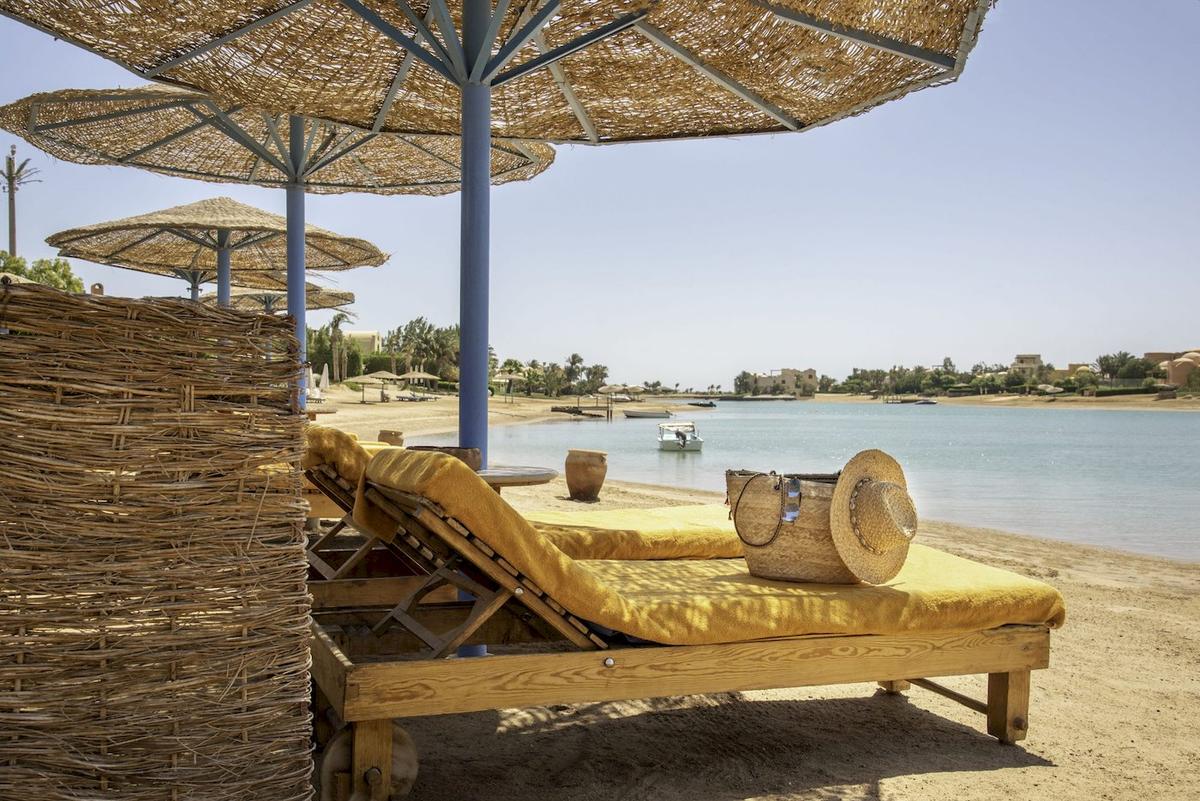 Strandbereich des Three Corners Rihana Resorts mit Liegen unter Sonnenschirmen und Blick auf den See.