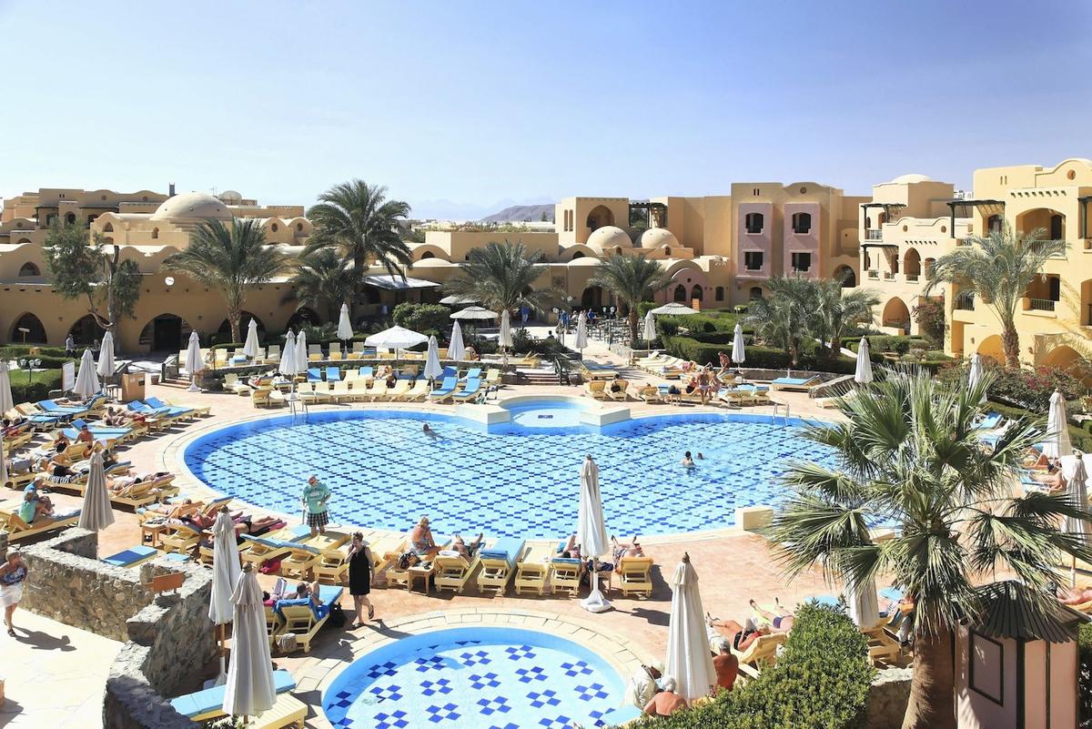 Ein Hotelpool mit vielen Sonnenliegen und Palmen, das Three Corners Rihana Resort.