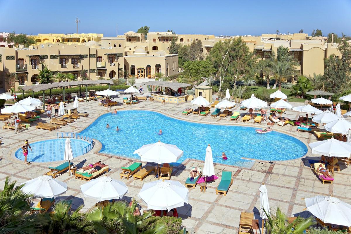 Ein Hotelkomplex mit mehreren Pools, Liegen, Sonnenschirmen und Gästebereichen.