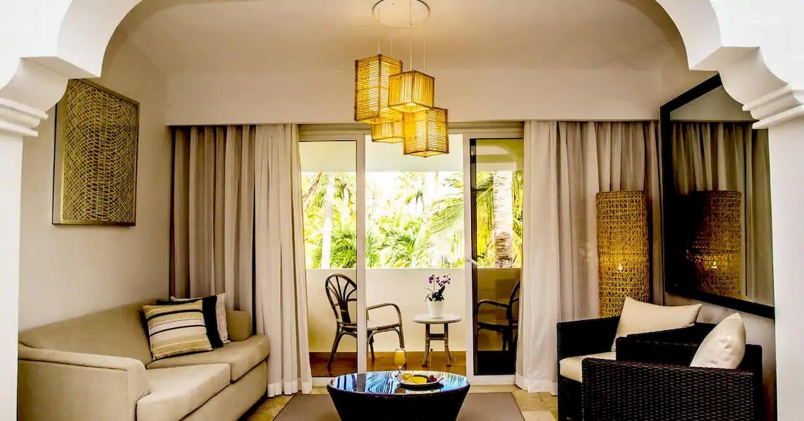 Wohnbereich des Melia Caribe Beach Resort mit Couch, Tisch und Glastüren.