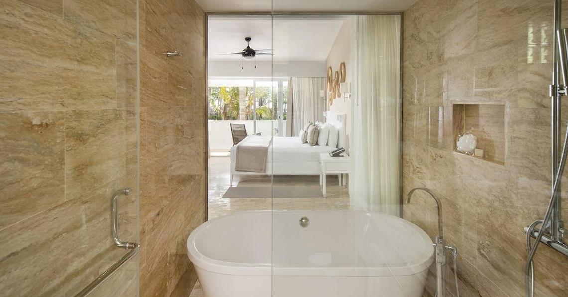 Badezimmer im Melia Caribe Beach Resort mit Badewanne, Dusche und Blick auf das Schlafzimmer.
