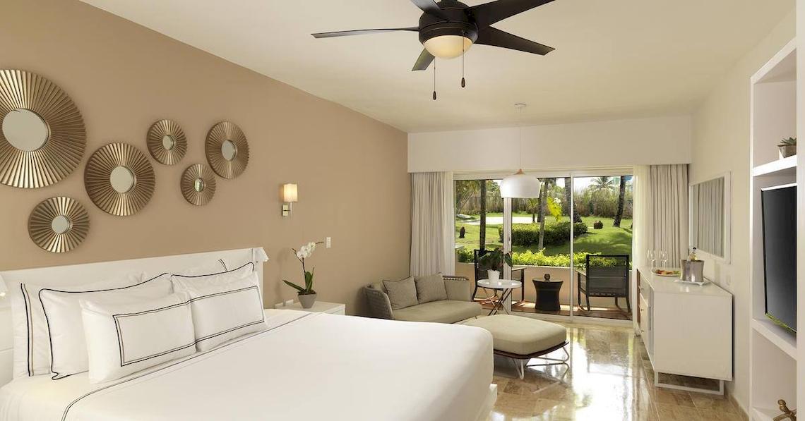 Luxuriöses Zimmer im Melia Caribe Beach Resort mit Bett, Sofa, Klimaanlage und Gartenblick.