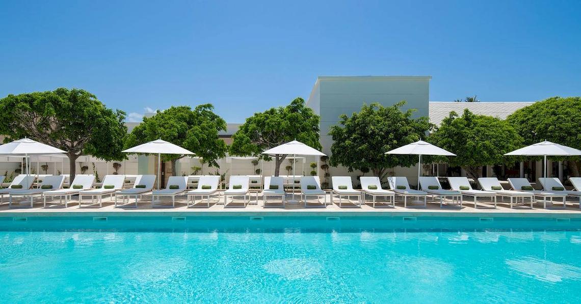Außenpoolbereich des Melia Caribe Beach Resort mit weißen Liegen und Sonnenschirmen.