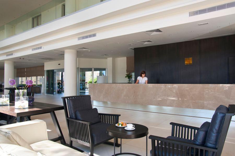 Empfangsbereich im Pernera Beach Hotel mit Rezeptionistin hinter dem Tresen.