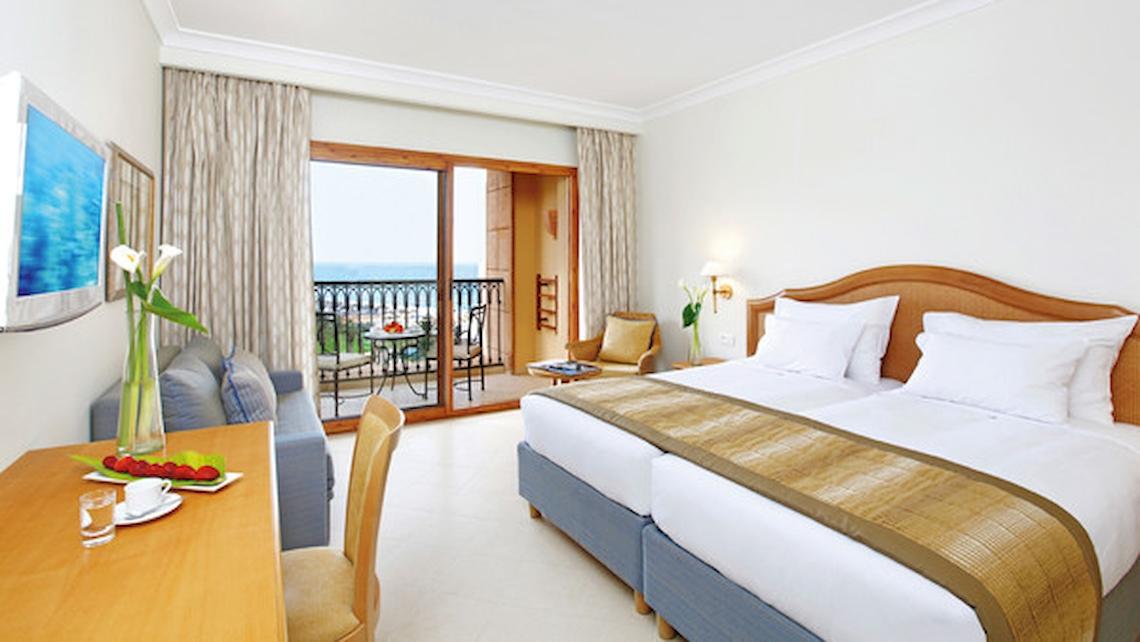 Hotelzimmer im Mövenpick Resort & Marine Spa Sousse mit Meerblick, Doppelbett, Balkon, Tisch und Sessel.