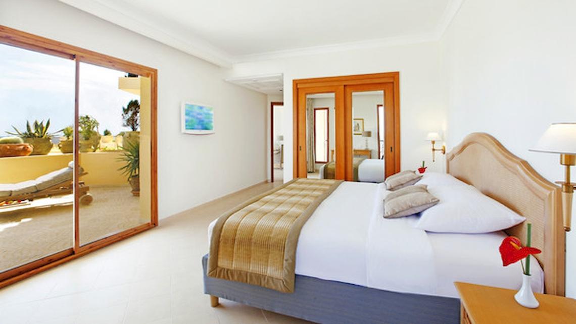 Schlafzimmer im Mövenpick Resort & Marine Spa Sousse mit Doppelbett, großer Glastür und Balkon