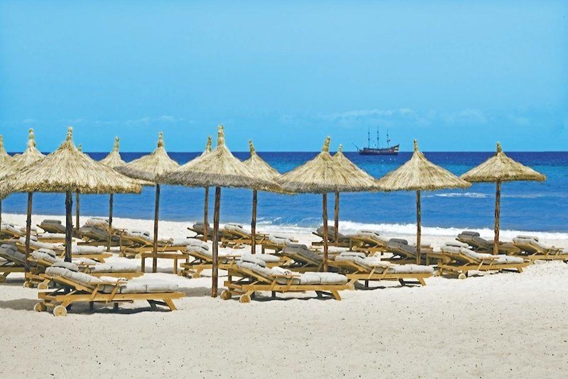 Strand des Mövenpick Resort & Marine Spa Sousse mit vielen Liegen und Strohschirmen