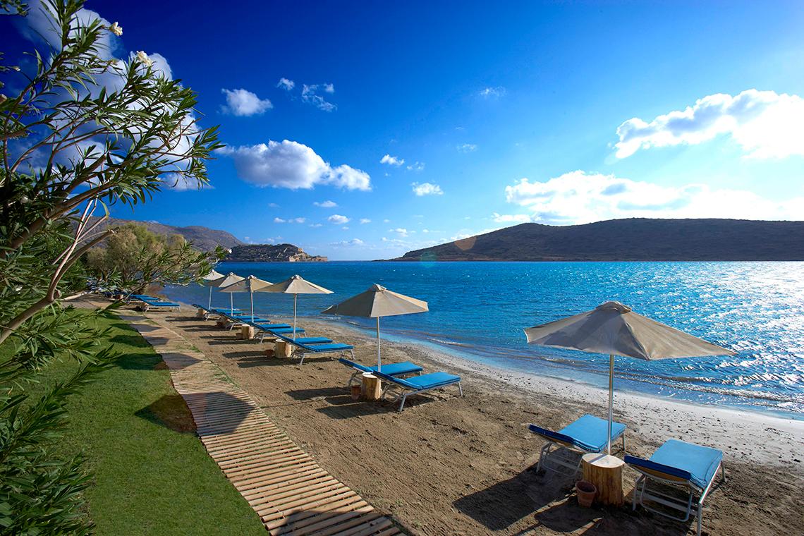 Domes of Elounda, Autograph Collection Strand mit Liegen und Sonnenschirmen