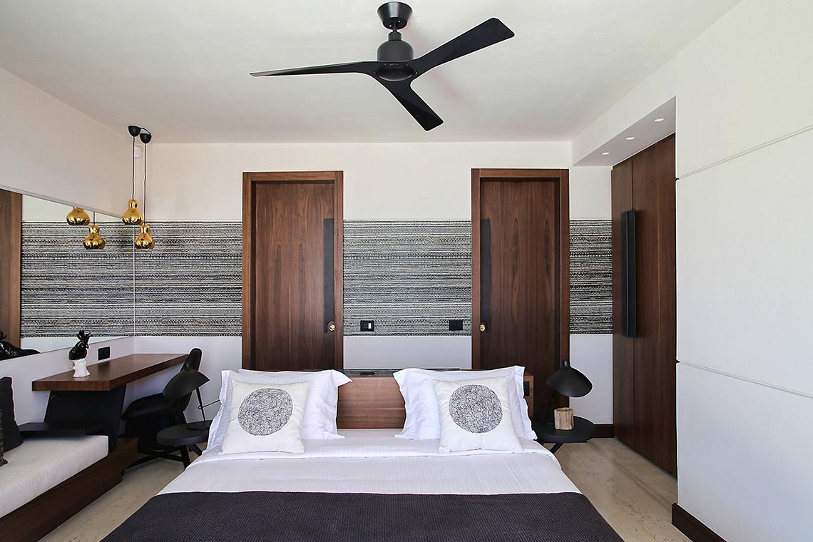 Schlafzimmer im Domes of Elounda, Autograph Collection mit einem Bett, zwei Kissen und einem Ventilator.