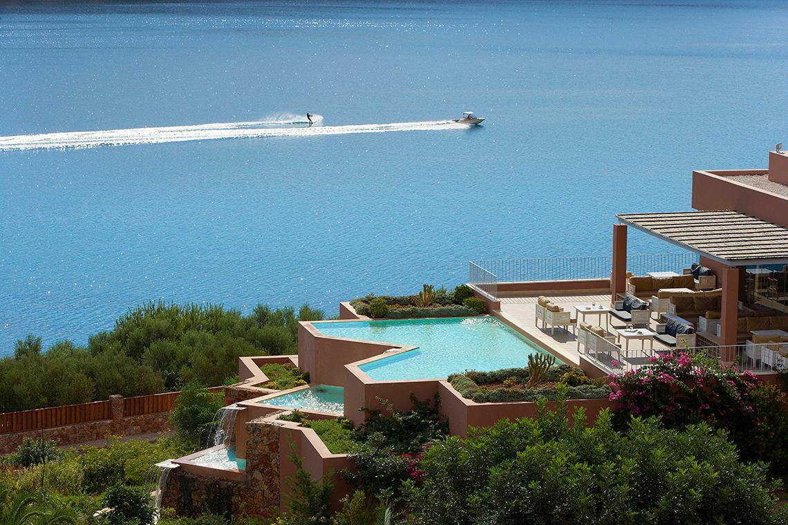 Aussicht auf Domes of Elounda mit Boot im Wasser und Wasserskifahrer