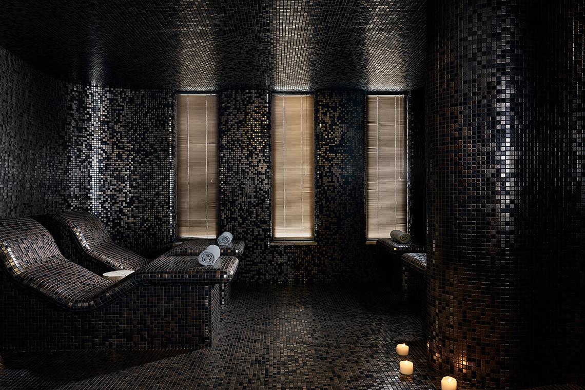 Spa-Bereich im Domes of Elounda, Autograph Collection mit schwarzen Mosaikfliesen und Liegestühlen.