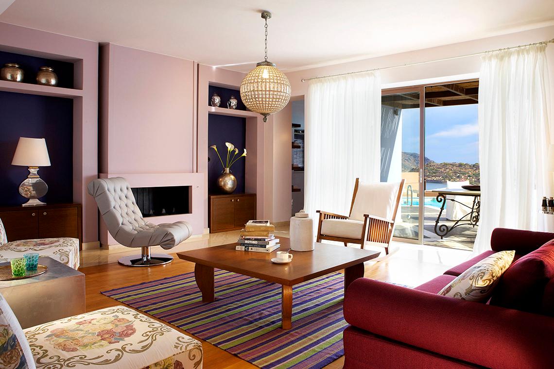 Wohnzimmer im Domes of Elounda, Autograph Collection mit gepolsterten Stühlen und einem Tisch.