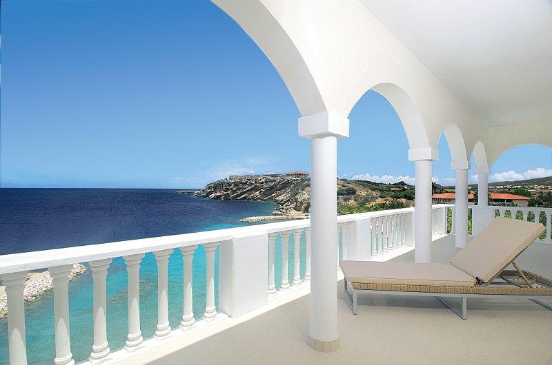 Balkon im Blue Bay Curacao Golf & Beach Resort mit Blick auf das Meer und eine Insel.