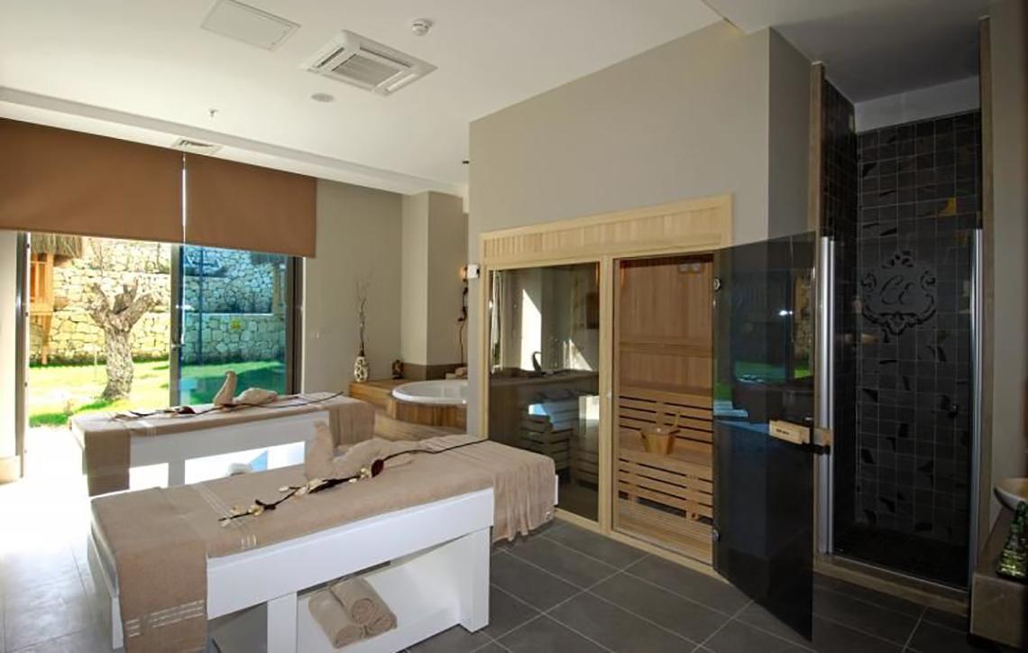 Behandlungsraum im Commodore Elite Suites & Spa mit zwei Massageliegen, Sauna und Badewanne.