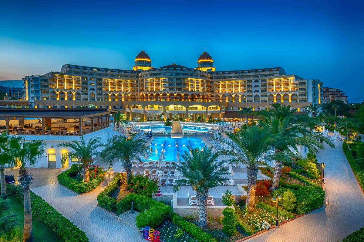 Außenansicht des Sidemarin Kirman Premium Hotels bei Nacht mit beleuchteter Fassade und Swimmingpool.