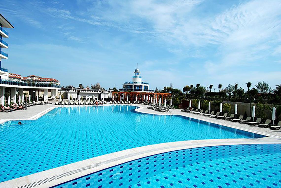 Außenpool mit Liegestühlen und Turm im Commodore Elite Suites & Spa Hotel.