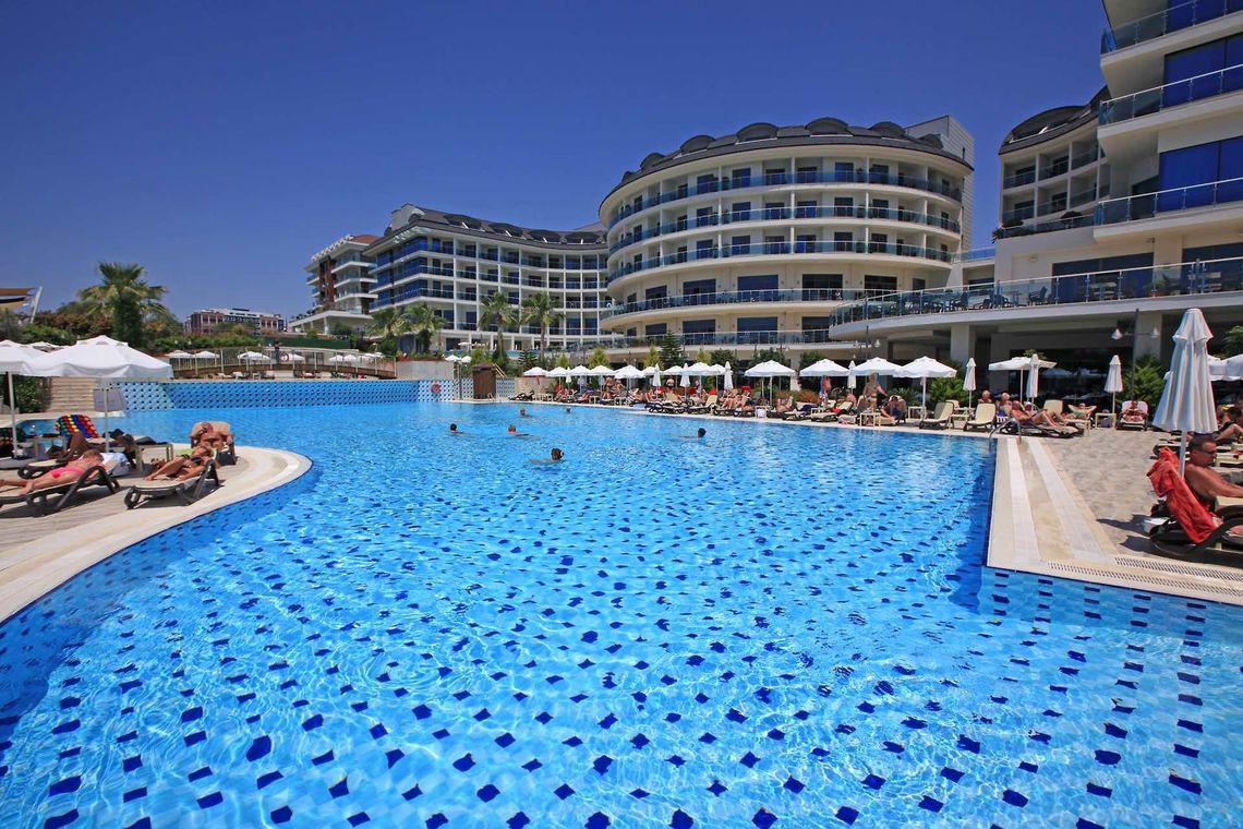 Außenpool des Commodore Elite Suites & Spa Hotels mit vielen Gästen und Liegestühlen.