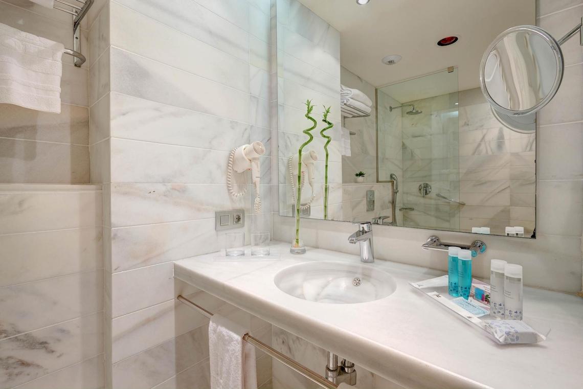Badezimmer des Hipotels Said mit weißem Marmor, Spiegel und Toilettenartikeln