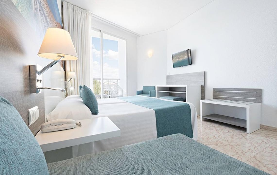 Ein modernes Hotelzimmer im Azuline Hotel Mar Amantis mit Doppelbett, Schreibtisch und Balkonzugang.
