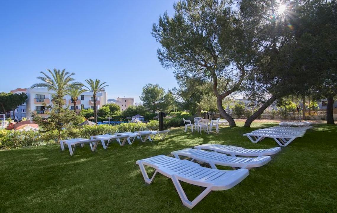 Gartenbereich des Azuline Hotel Mar Amantis I & II mit weißen Liegen auf grünem Rasen.