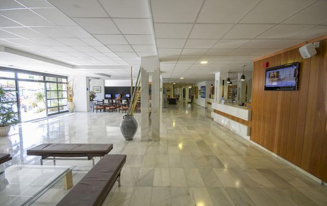 Empfangsbereich des Azuline Hotel Mar Amantis I & II mit Marmorboden, Holzwänden und Möbeln.