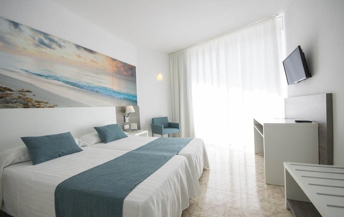 Innenansicht eines Doppelzimmers im Azuline Hotel Mar Amantis mit zwei Betten, Kissen und einem Fernseher an der Wand.