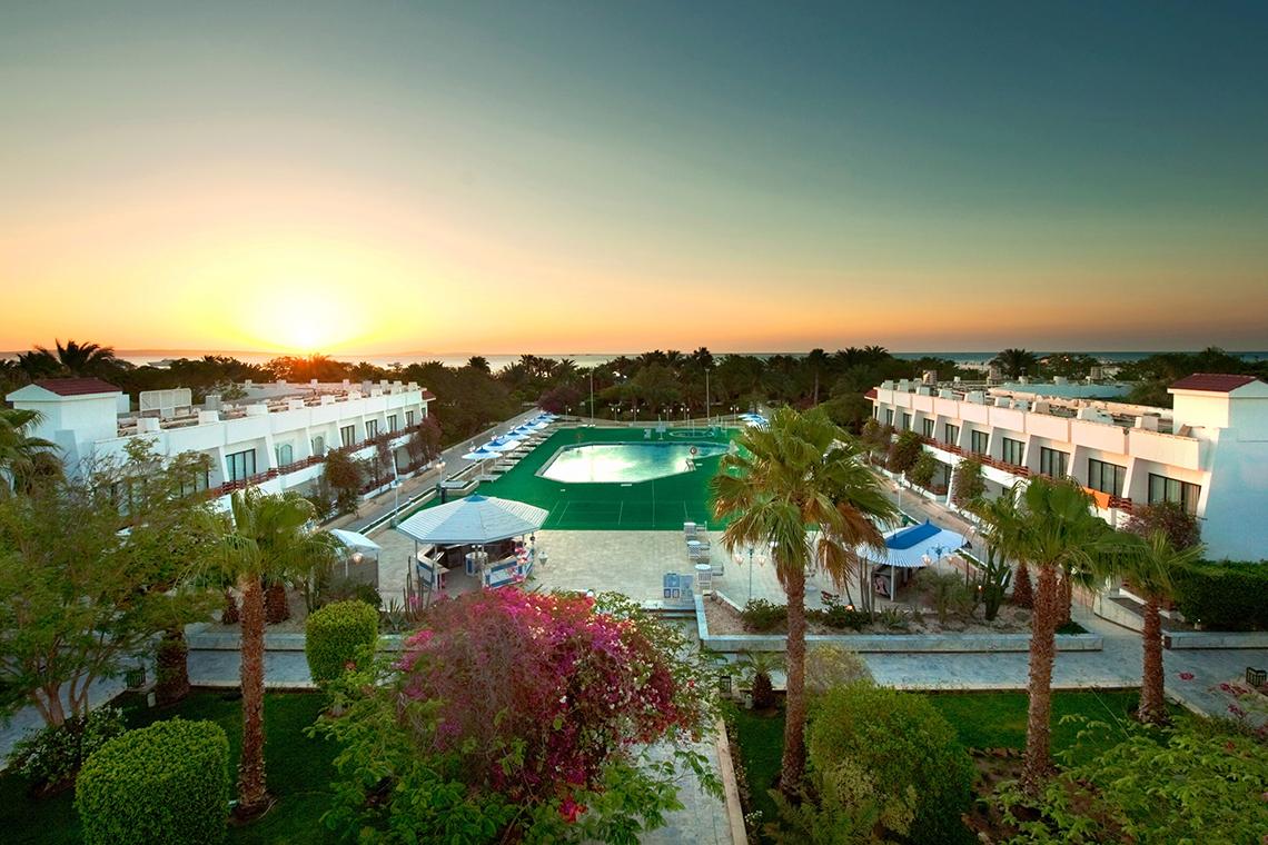 Aussicht auf das Grand Hotel Hurghada mit Pool und Sonnenuntergang im Hintergrund.