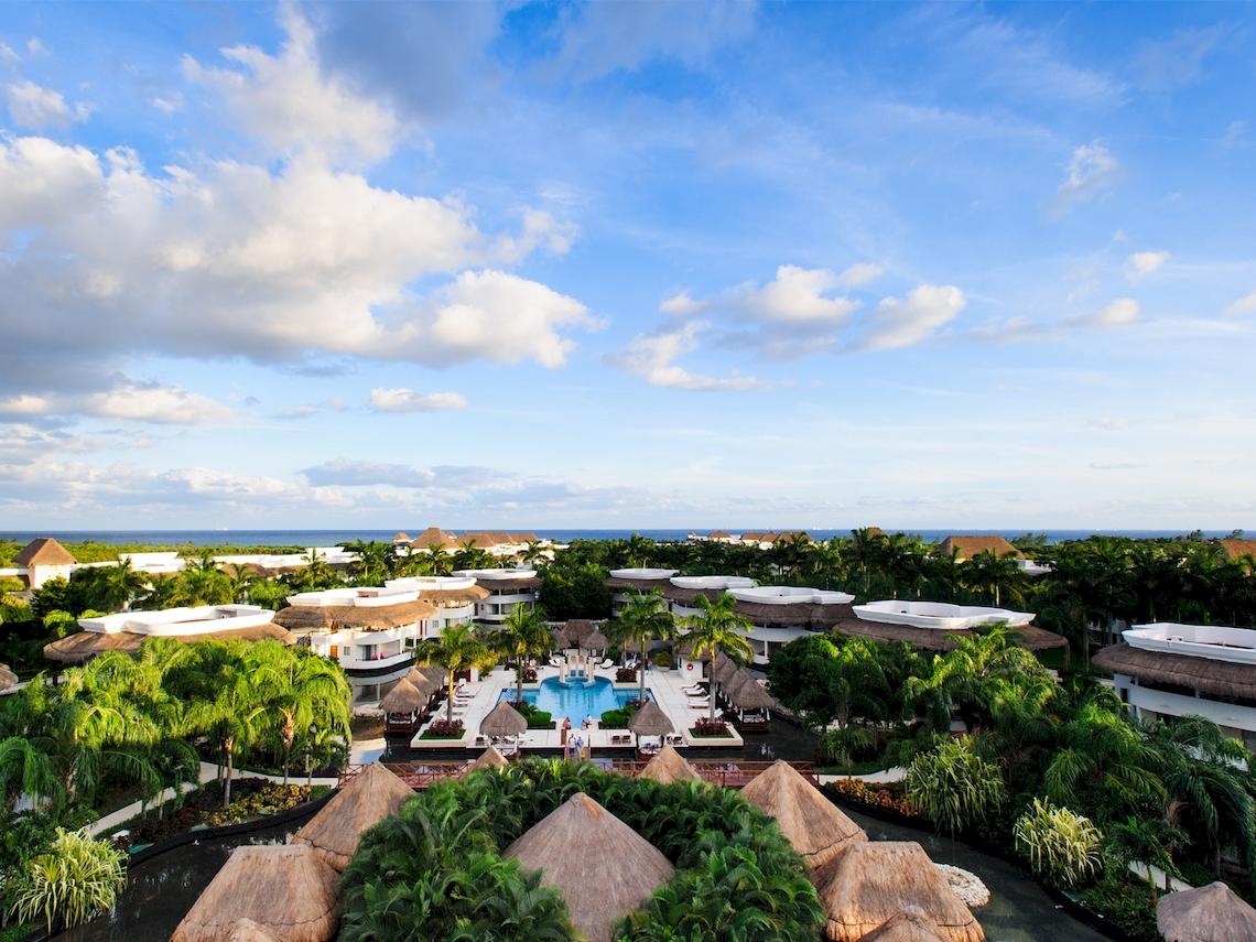Luftaufnahme des Grand Sunset Princess All Suites Resorts mit Pool und tropischen Pflanzen.