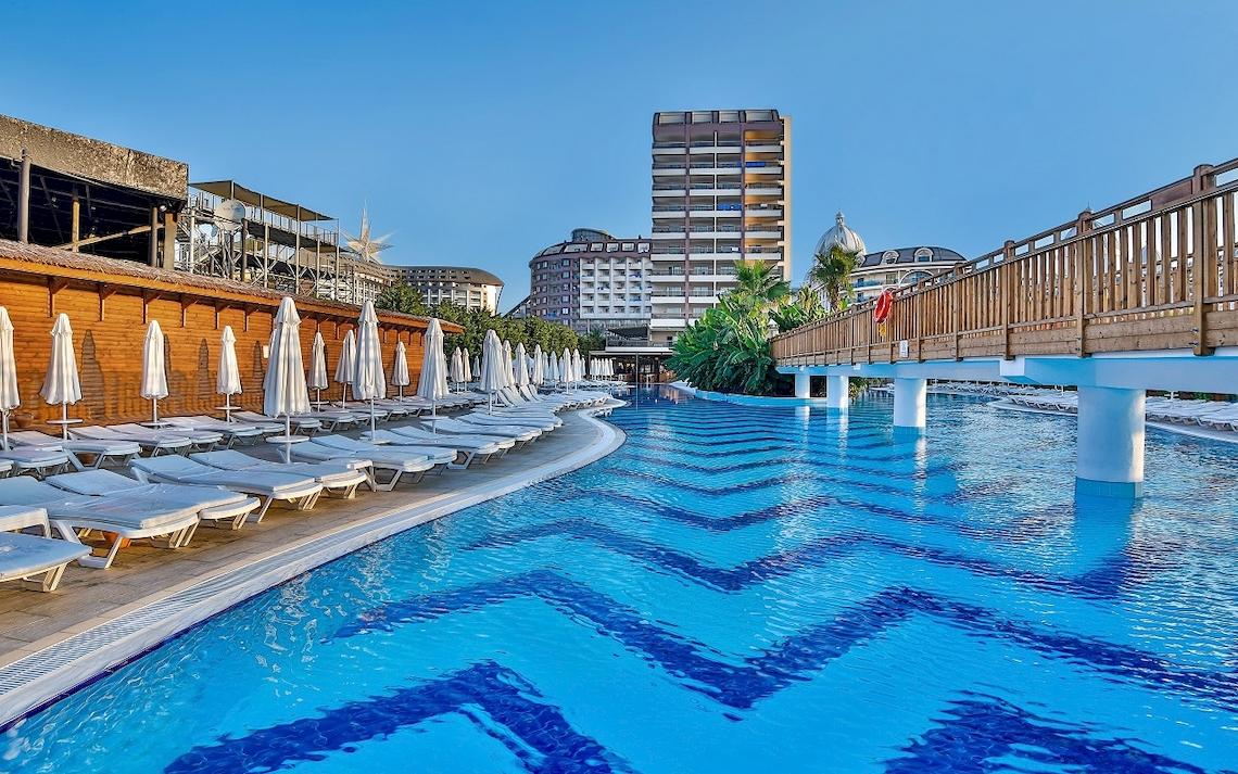 Der Poolbereich des Saturn Palace Resorts mit Liegestühlen und Sonnenschirmen.
