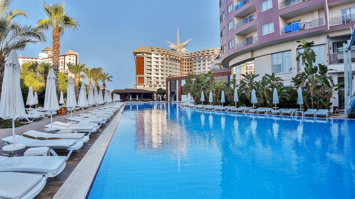 Außenpool des Saturn Palace Resorts mit weißen Liegen und Sonnenschirmen