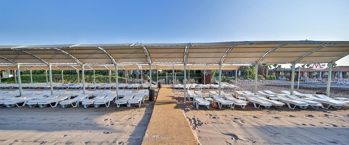 Strand mit vielen Liegestühlen unter Sonnenschirmen im Saturn Palace Resort