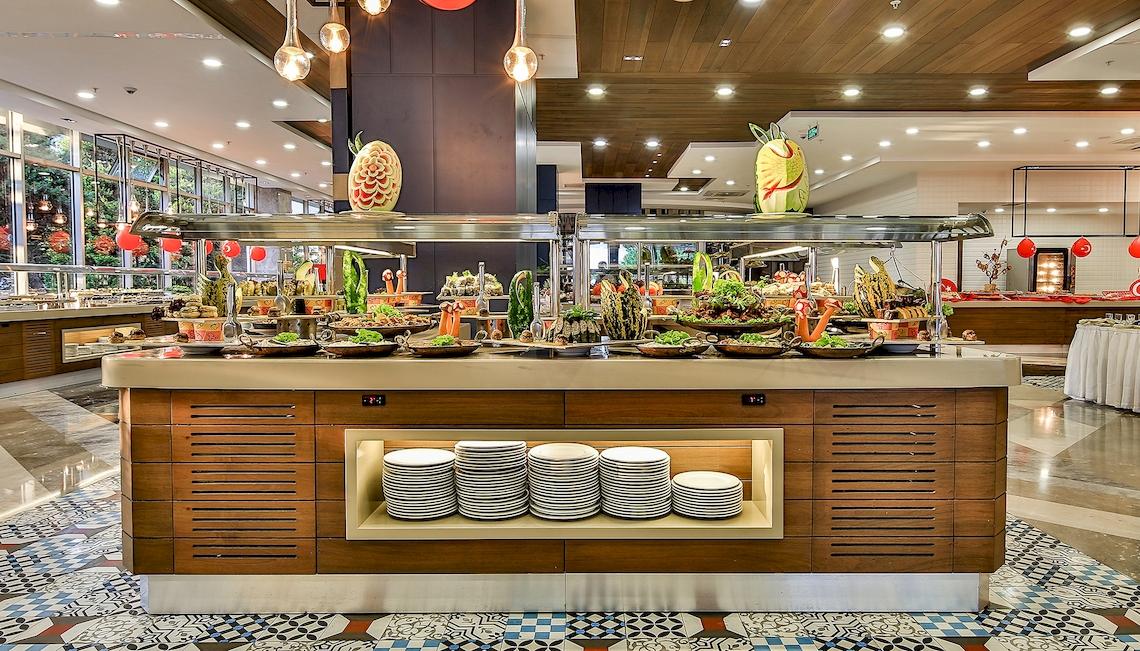 Buffet-Tisch im Saturn Palace Resort mit verschiedenen Speisen, darunter Salate, Früchte und Desserts.