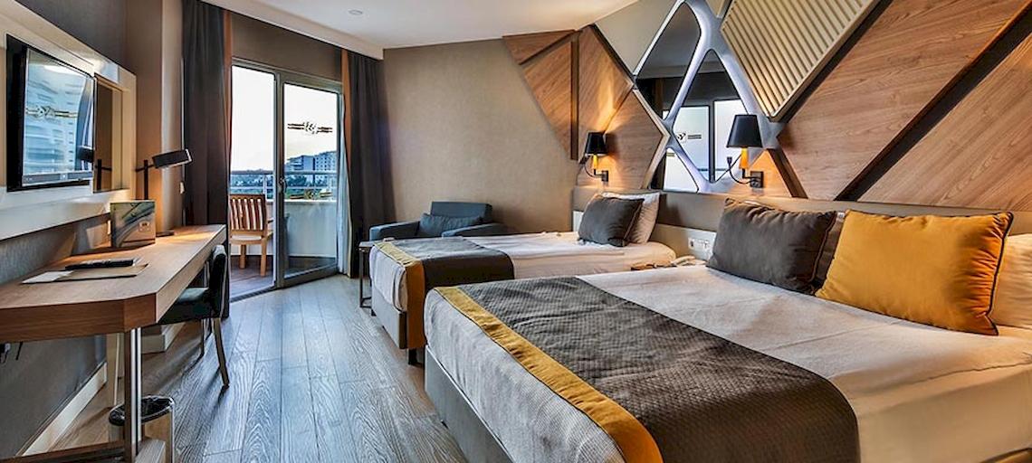Zwei Betten mit gelben und grauen Kissen in einem modernen Hotelzimmer des Saturn Palace Resort.